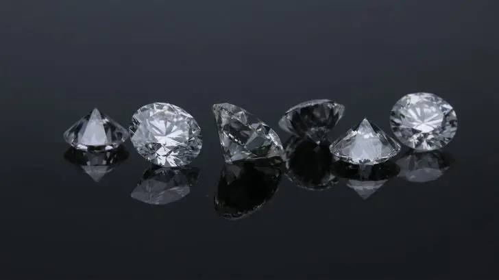 Are diamonds a good investment - A collection of five loose cut diamonds displayed on a reflective black surface.