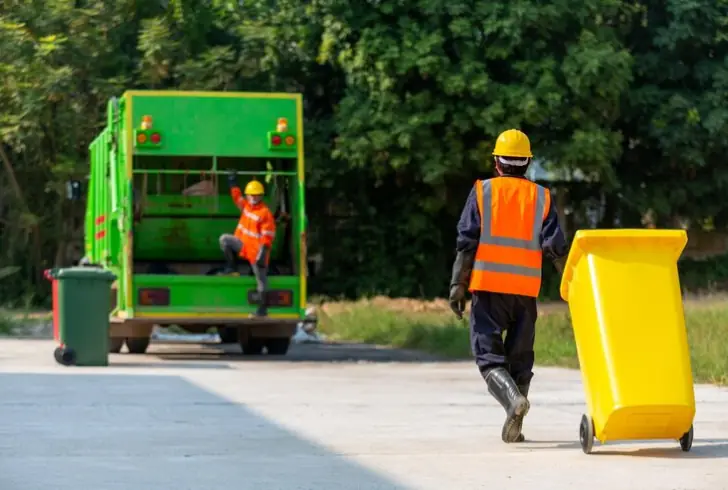 Workers collecting waste under tough conditions.
