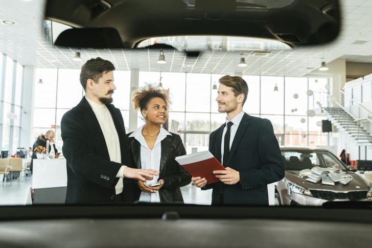 How do car salesman get paid - Image of a car salesman talking to a couple.t